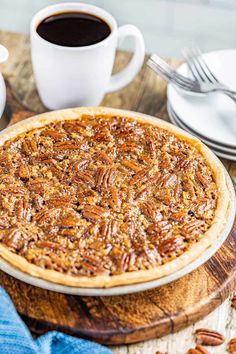 a pecan pie sitting on top of a wooden table next to two cups of coffee