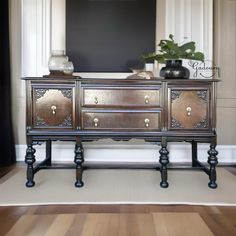 an ornate wooden dresser with two drawers in front of a black framed tv on the wall