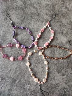 four bracelets with beads and flowers on them sitting on the floor next to each other