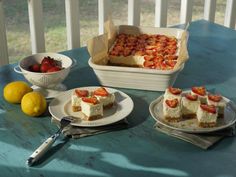 there are three pieces of cake on the table with strawberries and lemons next to it