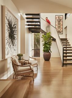 a living room filled with furniture and a stair case next to a painting on the wall