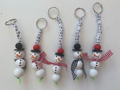 four snowmen wearing hats and scarfs with name tags attached to each keychain