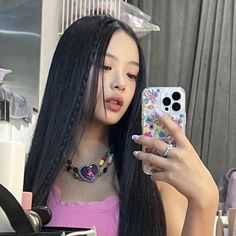 a woman with long black hair taking a selfie in front of her mirror while holding a cell phone