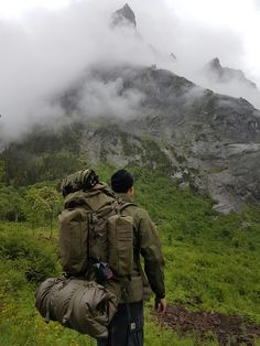 a man walking up a hill with backpacks on his back