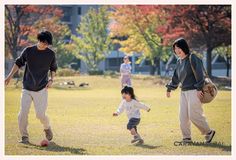 two adults and a child playing with a ball in a park on a sunny day