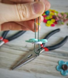 a person is holding scissors and string with buttons attached to the strings that are being held in front of them