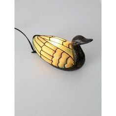 a yellow and black lamp with a bird on it's back end sitting on a white surface