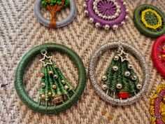 several different types of beaded christmas tree ornaments on a tablecloth with beads and rings around them