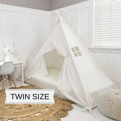 a white teepee tent sitting on top of a rug next to a table and chair