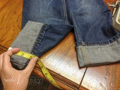 someone measuring their jeans with a tape measure