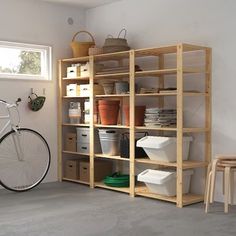 a bicycle is parked in front of a bookcase with baskets and containers on it