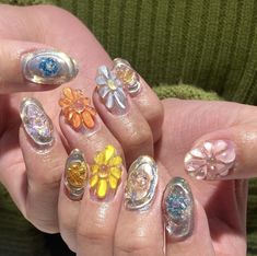 the woman is holding her nails with different designs on each nail and one has an orange flower in it