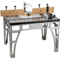 a table sawing machine sitting on top of a metal stand with two pieces of wood