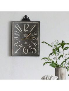 a clock hanging on the wall next to a potted plant