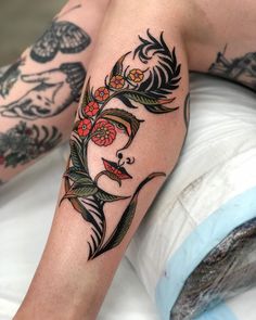 a woman's legs with tattoos and flowers on her head, sitting on a bed