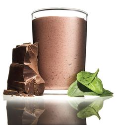 a glass filled with chocolate next to two pieces of green leafy leaves and a half - eaten piece of chocolate