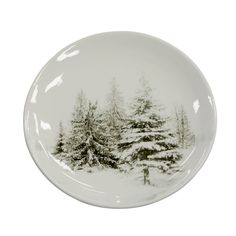 a white plate with trees painted on the side and snow on the ground, in front of a white background