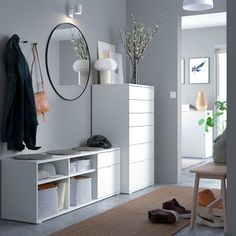 a room with white furniture and shoes on the floor next to a wall mounted mirror