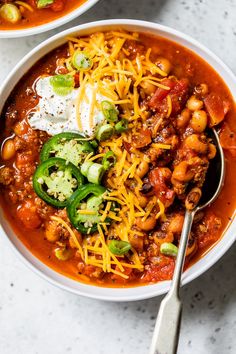 two bowls of chili and beans with sour cream on top