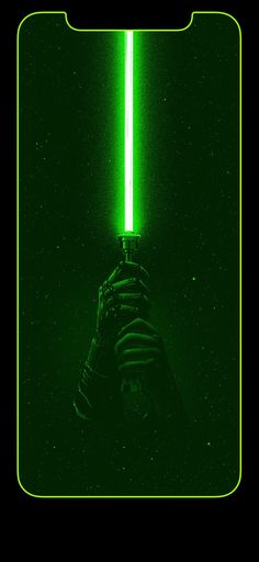 a person holding a green light saber in their hand with the lights on behind them