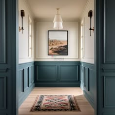 an empty hallway with blue painted walls and wood flooring, framed artwork on the wall