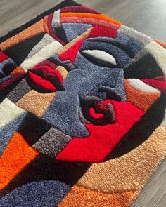 a multicolored area rug with an abstract face on the center and two different colors