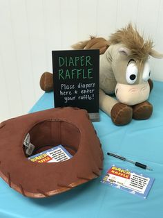 a stuffed animal sitting on top of a table next to a sign that says diaper raffle