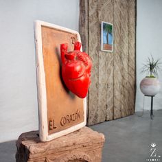 a red heart mounted to the side of a wooden plaque