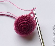 a crocheted ball of yarn next to a pair of knitting needles on a white surface