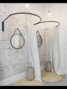 a white brick wall with round mirrors hanging from it's sides and curtains on the other side