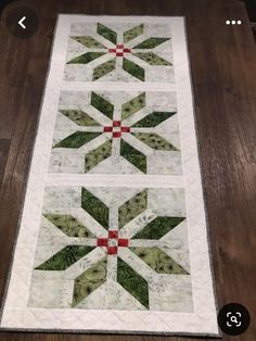 a quilted table runner with green and red designs on the top, along with an applique