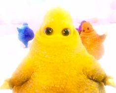 three little birds are sitting in the snow together, one is yellow and the other is blue