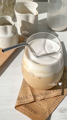 a table topped with two cups filled with liquid next to a wooden tray and measuring spoon