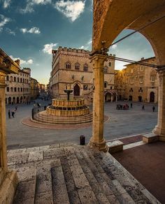 an old town square with people walking around and some buildings in the background at sunset