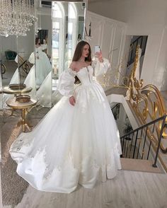 a woman in a white wedding dress taking a selfie with her cell phone while standing on stairs