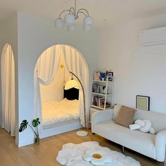 a living room filled with furniture and a white couch next to a book shelf on top of a hard wood floor