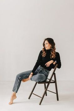 a woman sitting in a chair with her legs crossed and looking off to the side