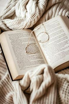 an open book on top of a bed next to a pair of glasses