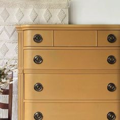 a yellow chest of drawers with knobs on the top and bottom, in front of a white wall