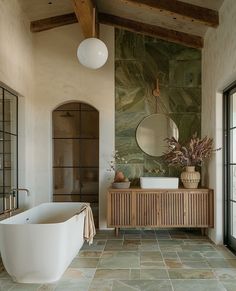 a bath room with a large tub next to a sink and a mirror on the wall