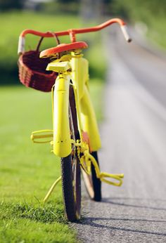 a yellow bike parked on the side of a road next to a grass covered field