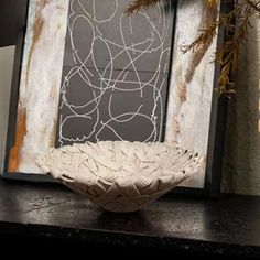 a white bowl sitting on top of a black table next to a framed photo and plant