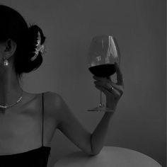 a woman sitting at a table with a glass of wine in front of her face