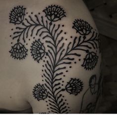 the back of a woman's shoulder with flowers and leaves tattoo on her left side