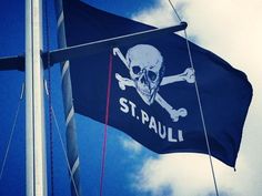 a flag with a skull and crossbones on it flying in the air next to a blue sky