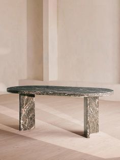 a marble table sitting on top of a hard wood floor next to a white wall