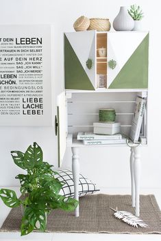 a green and white book shelf with books on it next to a potted plant