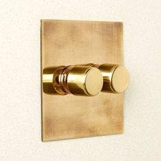 two knobs on the side of a gold plated wall mounted light switch in a bathroom