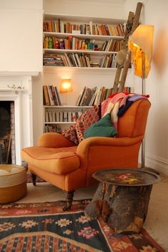 an orange chair sitting in front of a fire place next to a book shelf filled with books