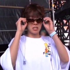 a woman wearing sunglasses and holding her hair in front of her face while standing on stage